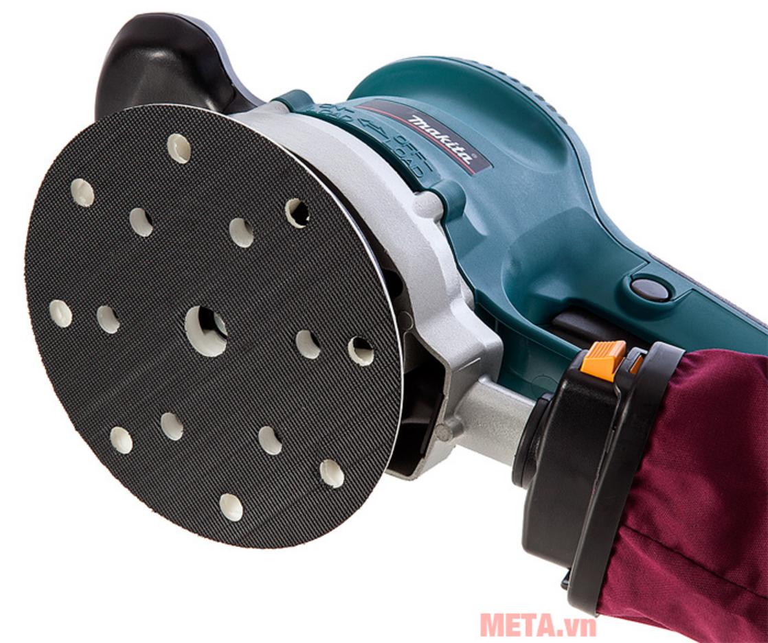 Công suất 310W và điều chỉnh tốc độ linh hoạt cho mọi bề mặt (gỗ, sơn).」「imagePrompt":"Close-up of the speed dial and motor housing of the Makita BO6030 in use on a wooden plank, showing motion blur on sanding disc and clear surface finish in frame.