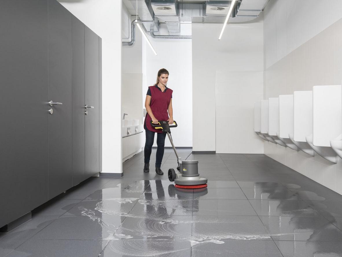 Động cơ 1.500 W của Karcher BDS 43/150 nâng cao hiệu suất làm sạch hàng giờ tương đương với công việc thủ công nhiều lần hơn so với máy nhỏ hơn, tăng năng suất đội vệ sinh tại doanh nghiệp. Image prompt: Close-up of the machine's motor and control panel, with a cleaner operating in the background, high-detail, commercial setting.
