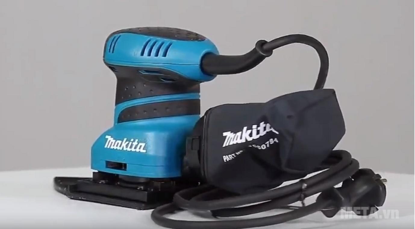 Worker holding Makita BO4565 with dust bag attached; shows ergonomics and lightweight design.