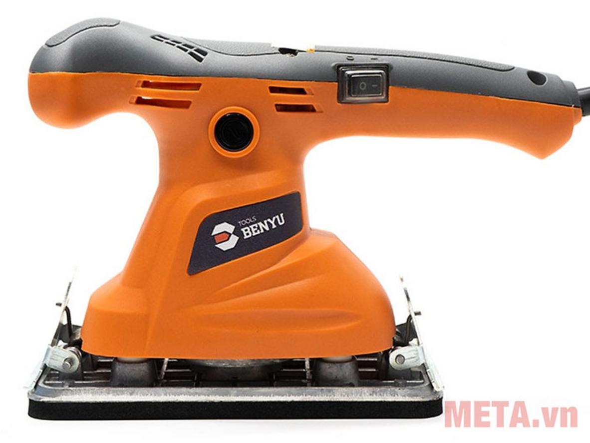 Close-up đế chà 98 x 180 mm trên bề mặt gỗ có vân tự nhiên, tay người cầm máy đang thao tác (ánh sáng ấm).