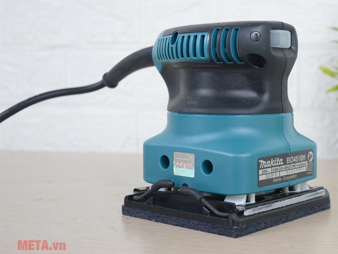 Công suất 170W và tốc độ cao giúp hoàn thiện bề mặt nhanh hơn trong xưởng nhỏ hoặc tại nhà DIY. ImagePrompt: Close-up of the sander running on a wooden board showing fine dust removal and a smooth finish.