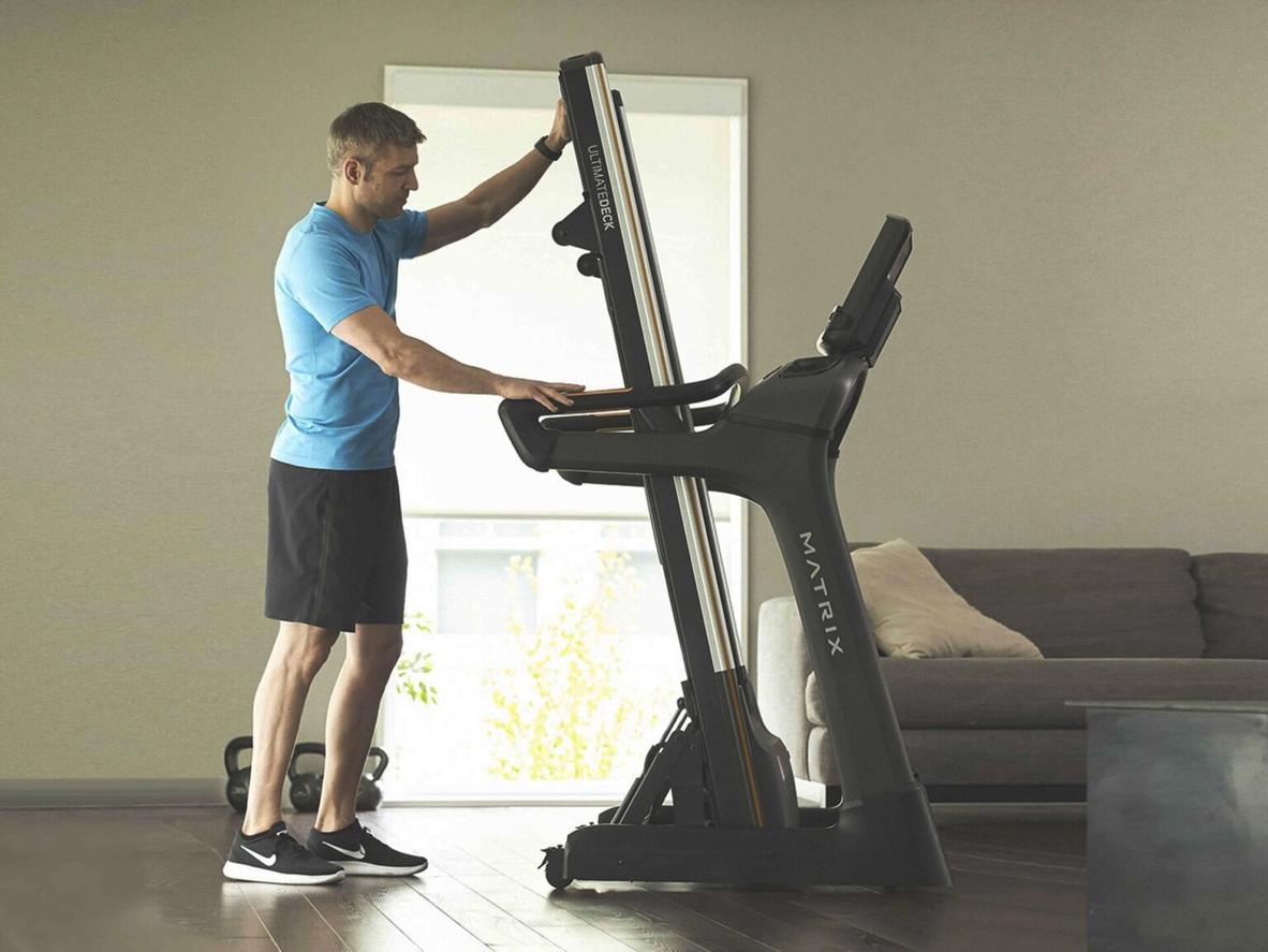 Bề mặt chạy rộng và hệ giảm chấn Ultimate Deck ,imagePrompt: "Wide shot of the treadmill belt showing 51x140 measurement and a runner's foot striking mid-stance"